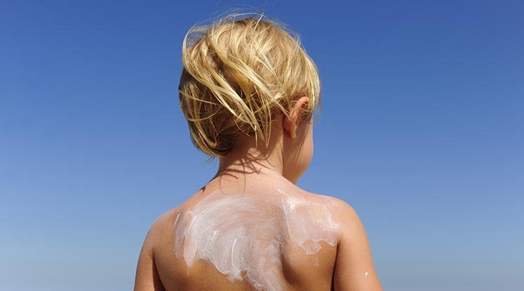 Kind mit Sonnencreme auf dem Rücken